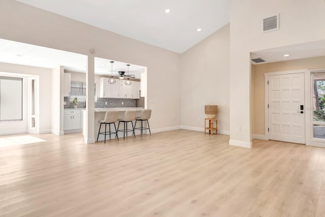 living room featuring light wood-type flooring, vaulted ceiling, and ceiling fan