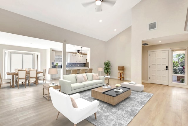 living room featuring ceiling fan, high vaulted ceiling, and light hardwood / wood-style floors