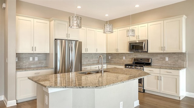 kitchen with appliances with stainless steel finishes, decorative light fixtures, tasteful backsplash, and sink