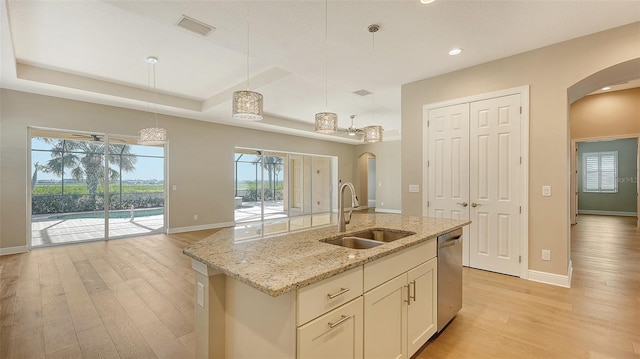 kitchen featuring stainless steel dishwasher, a healthy amount of sunlight, a center island with sink, and sink