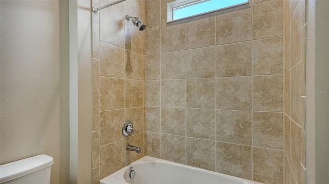 bathroom featuring tiled shower / bath and toilet