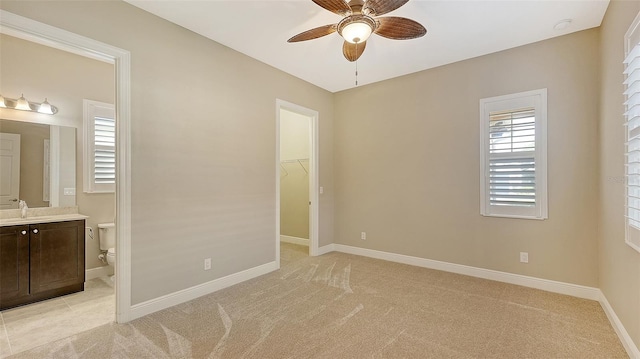 unfurnished bedroom featuring ceiling fan, light carpet, and a spacious closet