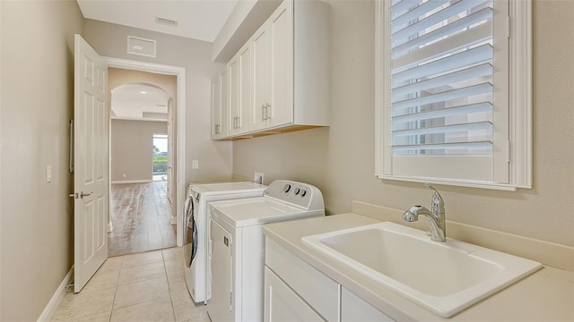 clothes washing area with cabinets, independent washer and dryer, sink, and light tile patterned floors