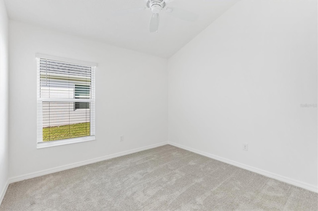 empty room with ceiling fan, light colored carpet, and vaulted ceiling