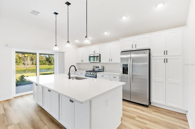 kitchen with sink, hanging light fixtures, stainless steel appliances, a kitchen island with sink, and white cabinets