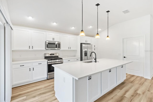 kitchen with white cabinets, decorative light fixtures, a kitchen island with sink, and appliances with stainless steel finishes