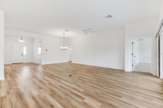 unfurnished living room featuring ceiling fan with notable chandelier and light wood-type flooring