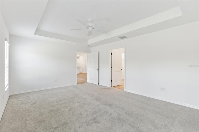 carpeted spare room featuring ceiling fan and a tray ceiling