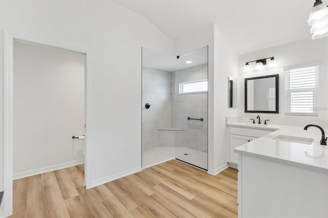 bathroom with tiled shower, vanity, hardwood / wood-style flooring, and lofted ceiling