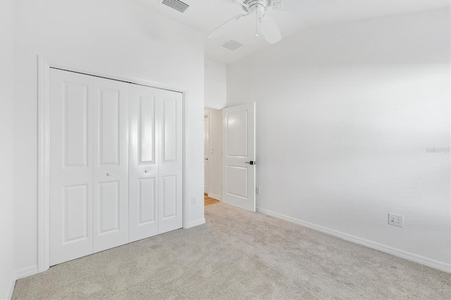 unfurnished bedroom with light carpet, vaulted ceiling, a closet, and ceiling fan