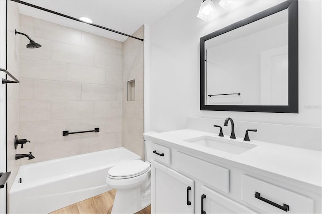 full bathroom featuring hardwood / wood-style flooring, tiled shower / bath combo, toilet, and vanity