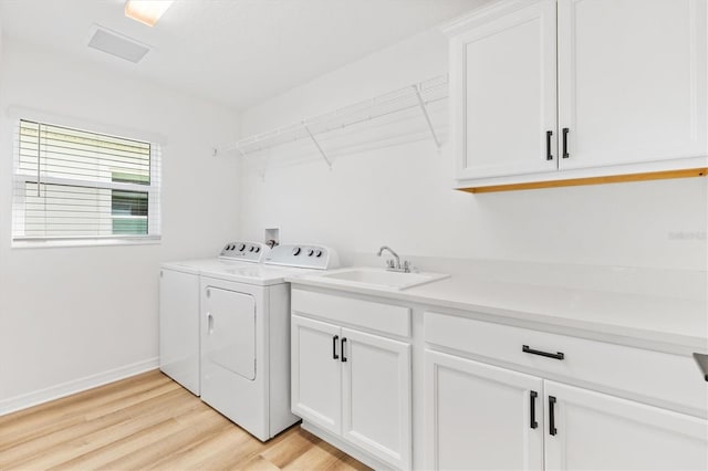 laundry area featuring washer and clothes dryer, light hardwood / wood-style flooring, cabinets, and sink