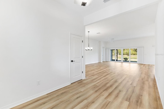 empty room featuring ceiling fan with notable chandelier and light hardwood / wood-style flooring