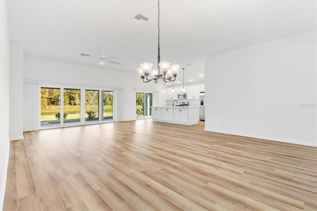 unfurnished living room featuring ceiling fan with notable chandelier and light hardwood / wood-style floors