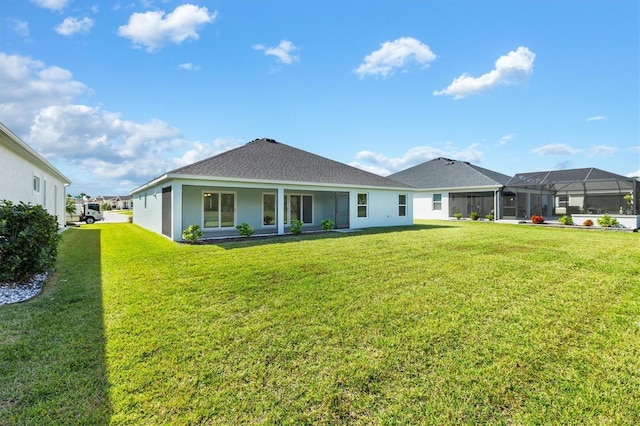 rear view of property featuring a lawn and glass enclosure