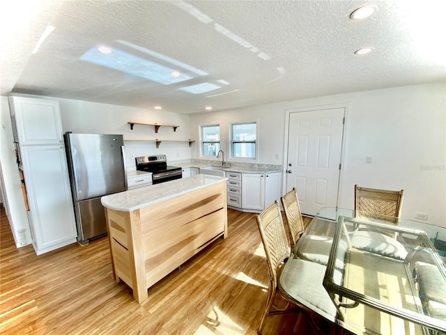 kitchen featuring a textured ceiling, white cabinetry, stainless steel appliances, and light hardwood / wood-style flooring