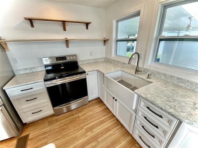 kitchen with white cabinetry, sink, light stone countertops, stainless steel electric stove, and light wood-type flooring