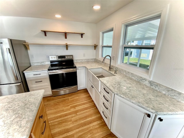 kitchen featuring sink, stainless steel appliances, light stone counters, light hardwood / wood-style flooring, and white cabinets