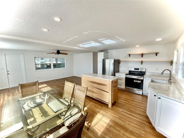 kitchen with a textured ceiling, light hardwood / wood-style floors, sink, and appliances with stainless steel finishes