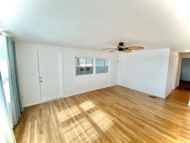 unfurnished living room with a textured ceiling, light wood-type flooring, and ceiling fan