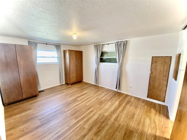 unfurnished bedroom with stainless steel refrigerator, a textured ceiling, and light wood-type flooring