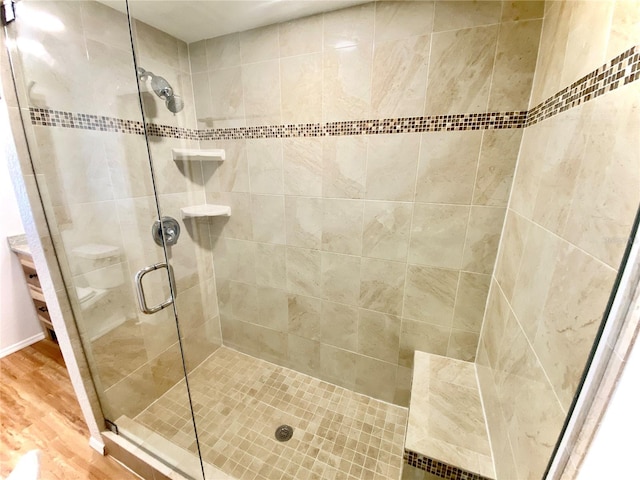 bathroom with wood-type flooring, toilet, and a shower with shower door