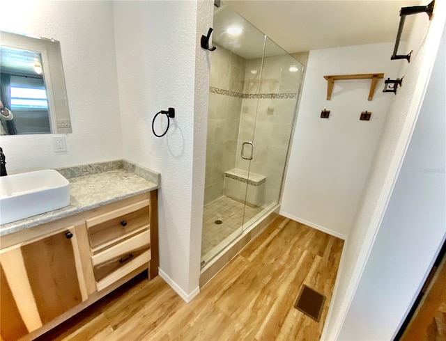 bathroom with hardwood / wood-style floors, vanity, and a shower with door