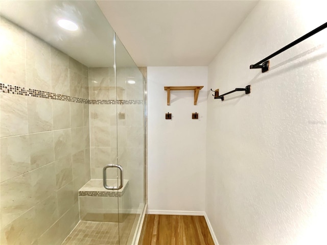 bathroom with a shower with shower door and hardwood / wood-style flooring