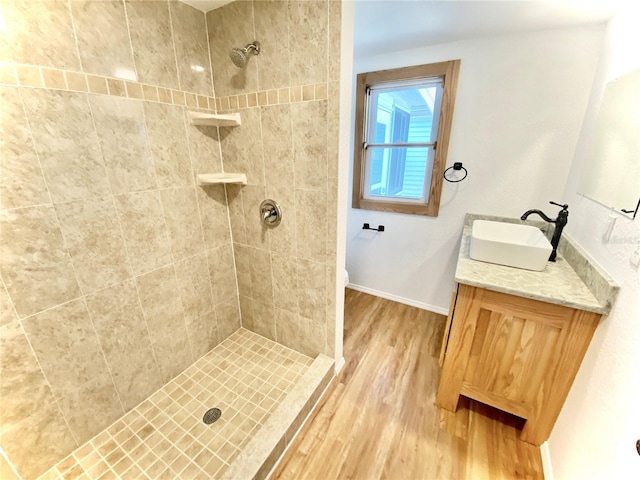 bathroom featuring hardwood / wood-style flooring, vanity, and tiled shower