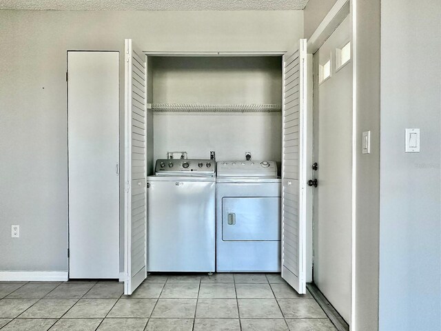 laundry room with washer and dryer, a textured ceiling, and light tile patterned flooring