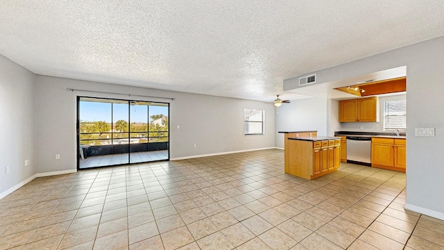 kitchen featuring stainless steel dishwasher, light tile patterned floors, a textured ceiling, and a wealth of natural light