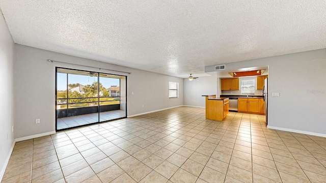 interior space featuring ceiling fan, light tile patterned flooring, and a textured ceiling