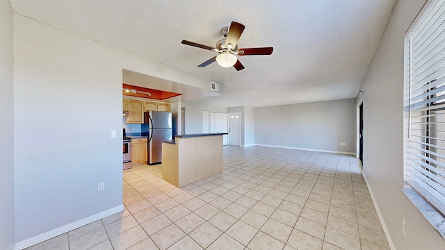 interior space with a textured ceiling, ceiling fan, light tile patterned floors, and stainless steel appliances