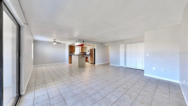 unfurnished living room with a textured ceiling, ceiling fan, and light tile patterned flooring