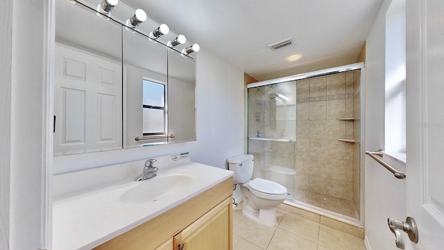 bathroom featuring toilet, vanity, tile patterned floors, and a shower with door