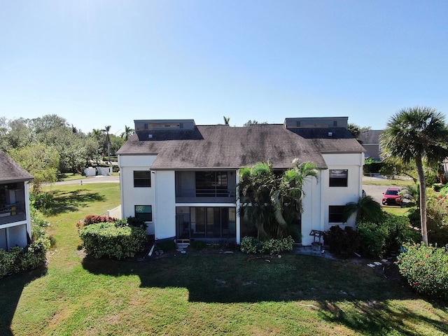 back of house featuring a lawn and a sunroom