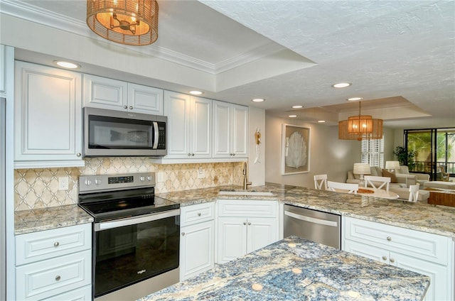 kitchen featuring sink, hanging light fixtures, a raised ceiling, white cabinets, and appliances with stainless steel finishes