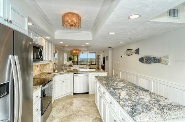 kitchen with white cabinets, sink, ornamental molding, and stainless steel appliances