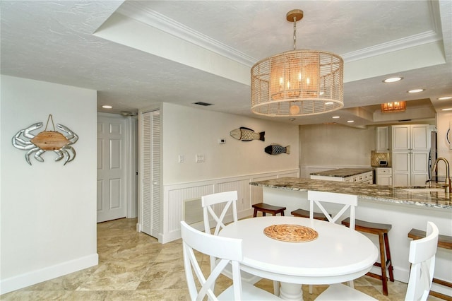 dining area with crown molding, sink, a textured ceiling, and an inviting chandelier