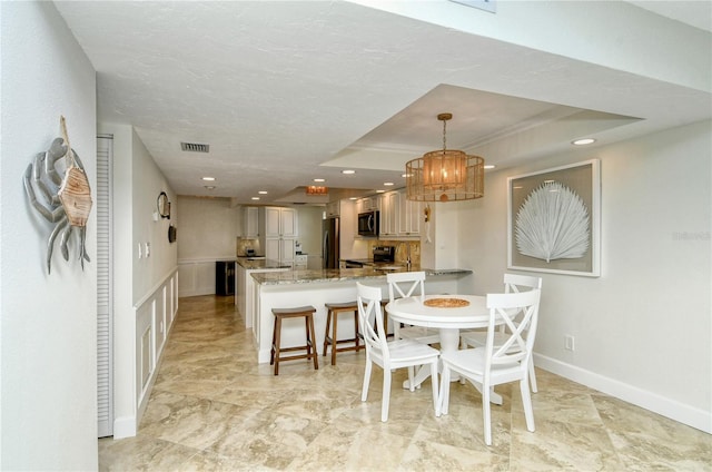 dining room with a textured ceiling, an inviting chandelier, a raised ceiling, and sink