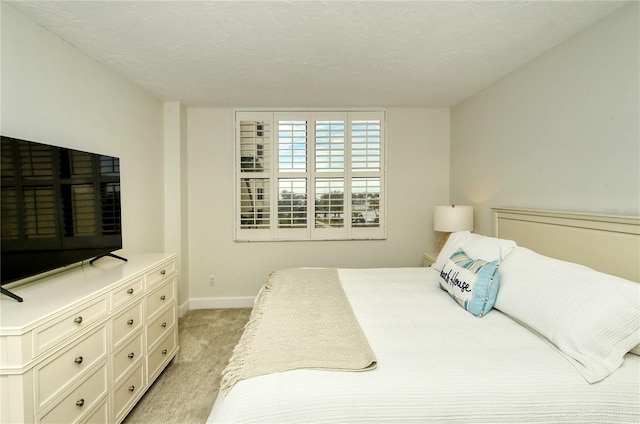 bedroom featuring light carpet and a textured ceiling