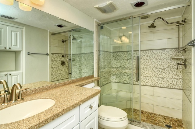 bathroom featuring a textured ceiling, vanity, toilet, and walk in shower