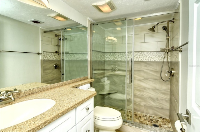 bathroom with a textured ceiling, vanity, an enclosed shower, and toilet