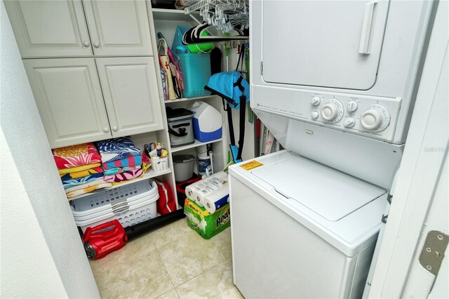 washroom with cabinets, stacked washer / dryer, and light tile patterned flooring