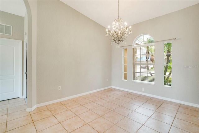 empty room featuring an inviting chandelier, lofted ceiling, and light tile patterned flooring