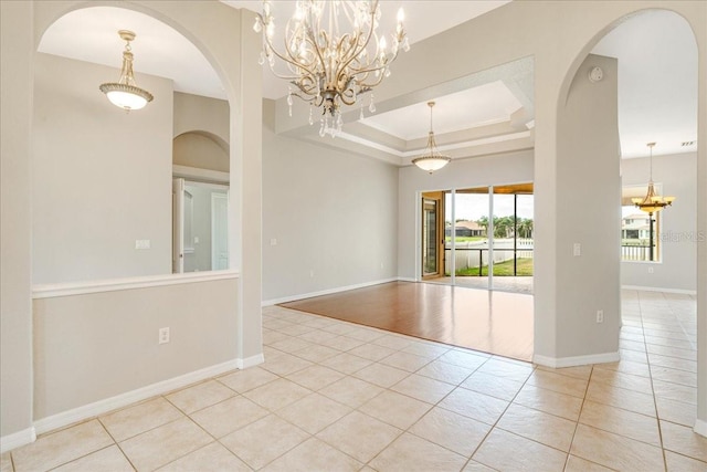 tiled empty room featuring a raised ceiling