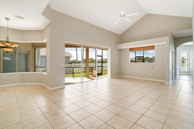 tiled spare room with ceiling fan with notable chandelier, high vaulted ceiling, and a healthy amount of sunlight