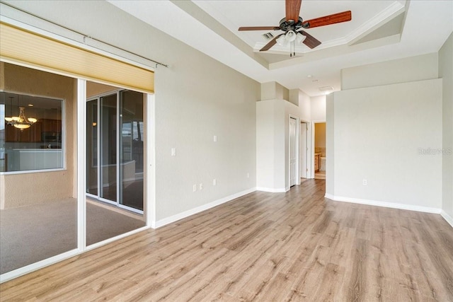 unfurnished room with ceiling fan, a raised ceiling, ornamental molding, and light hardwood / wood-style flooring