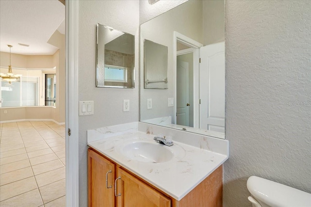 bathroom featuring a chandelier, vanity, toilet, and tile patterned flooring