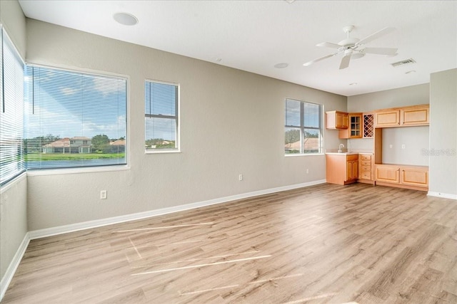 unfurnished living room featuring built in desk, light hardwood / wood-style floors, and ceiling fan